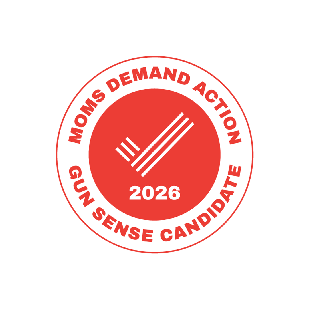 A circular red and white badge with the text "Mom's Demand Action GUN SENSE CANDIDATE 2026" around the border. The center features a checkmark made of three parallel lines.