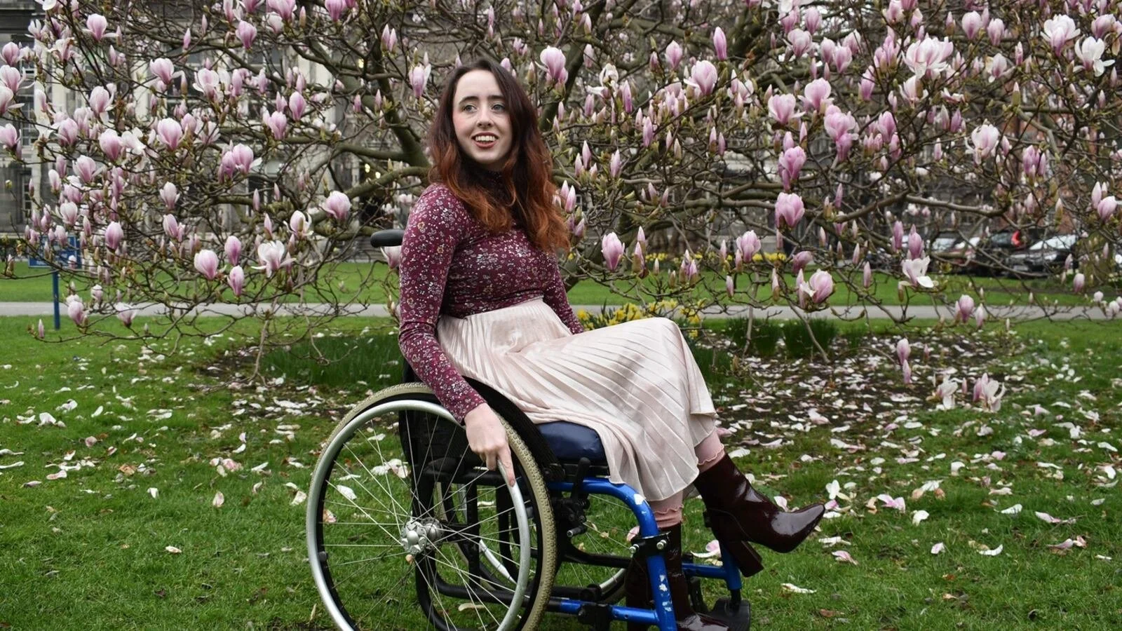 A woman (Niamh Ní Hoireabhaird) sitting in her wheelchair and smiling.