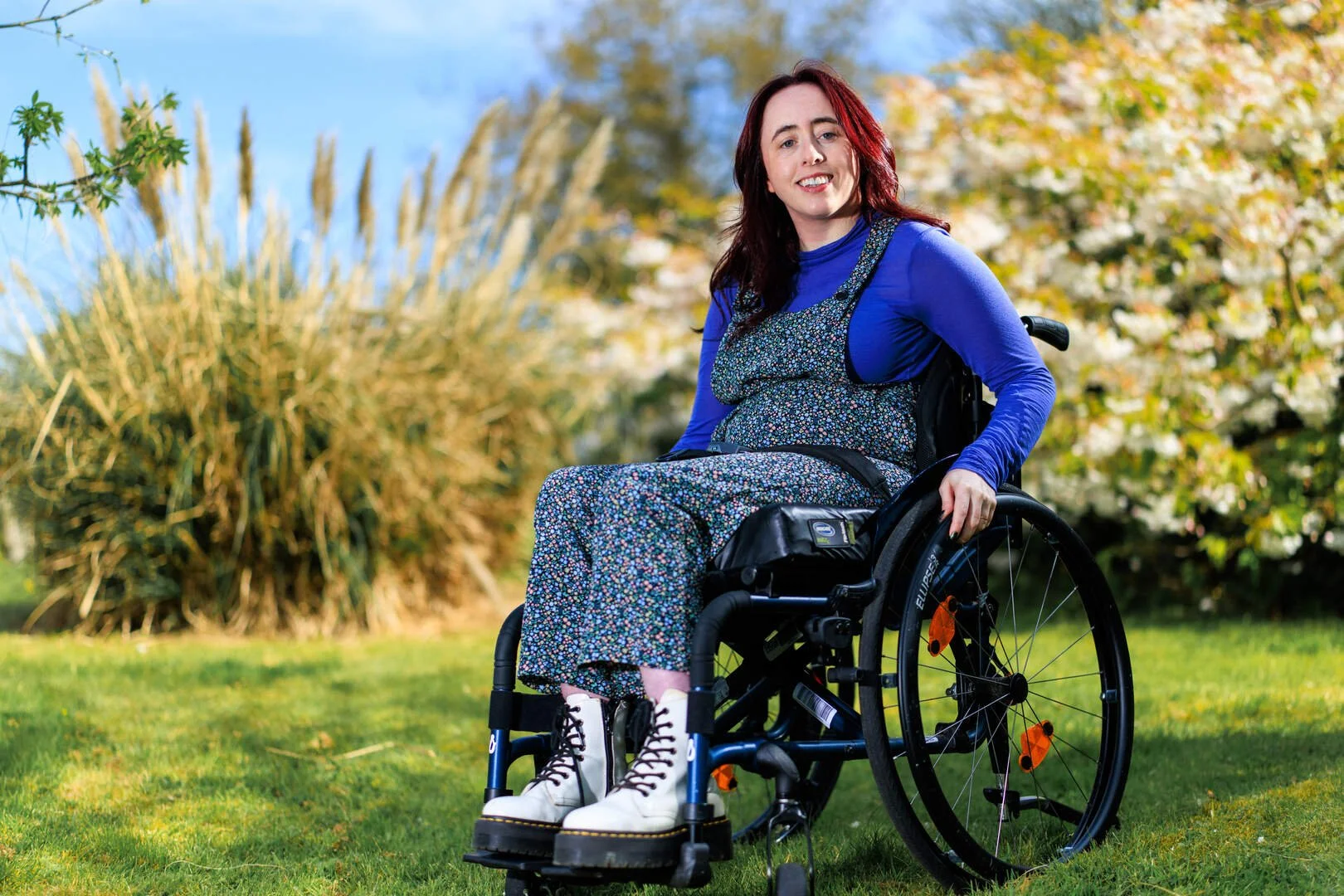 A woman (Niamh Ní Hoireabhaird) in her wheelchair, outside on the grass