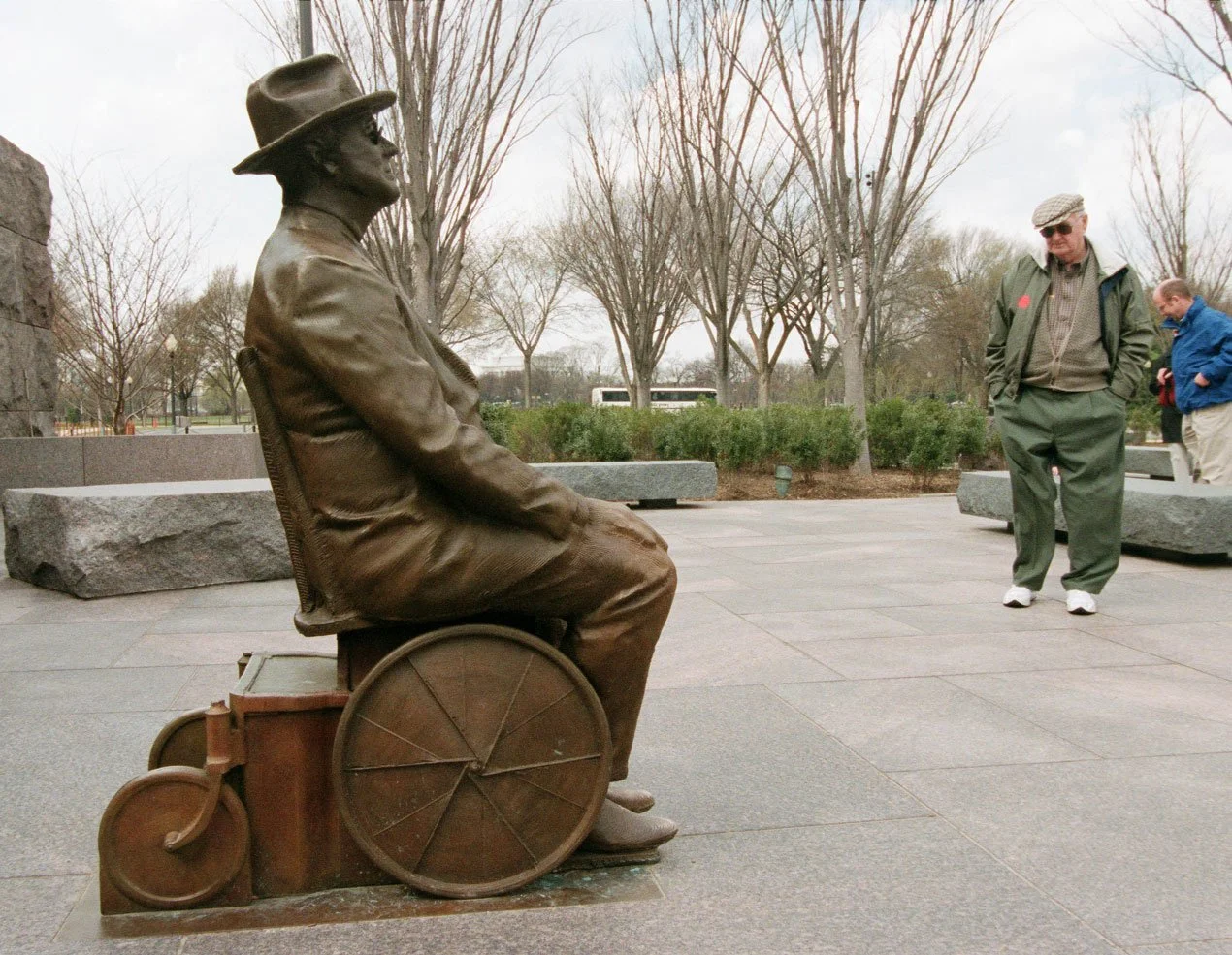A bronze statue of a man (FDR) sitting in a small wheelchair