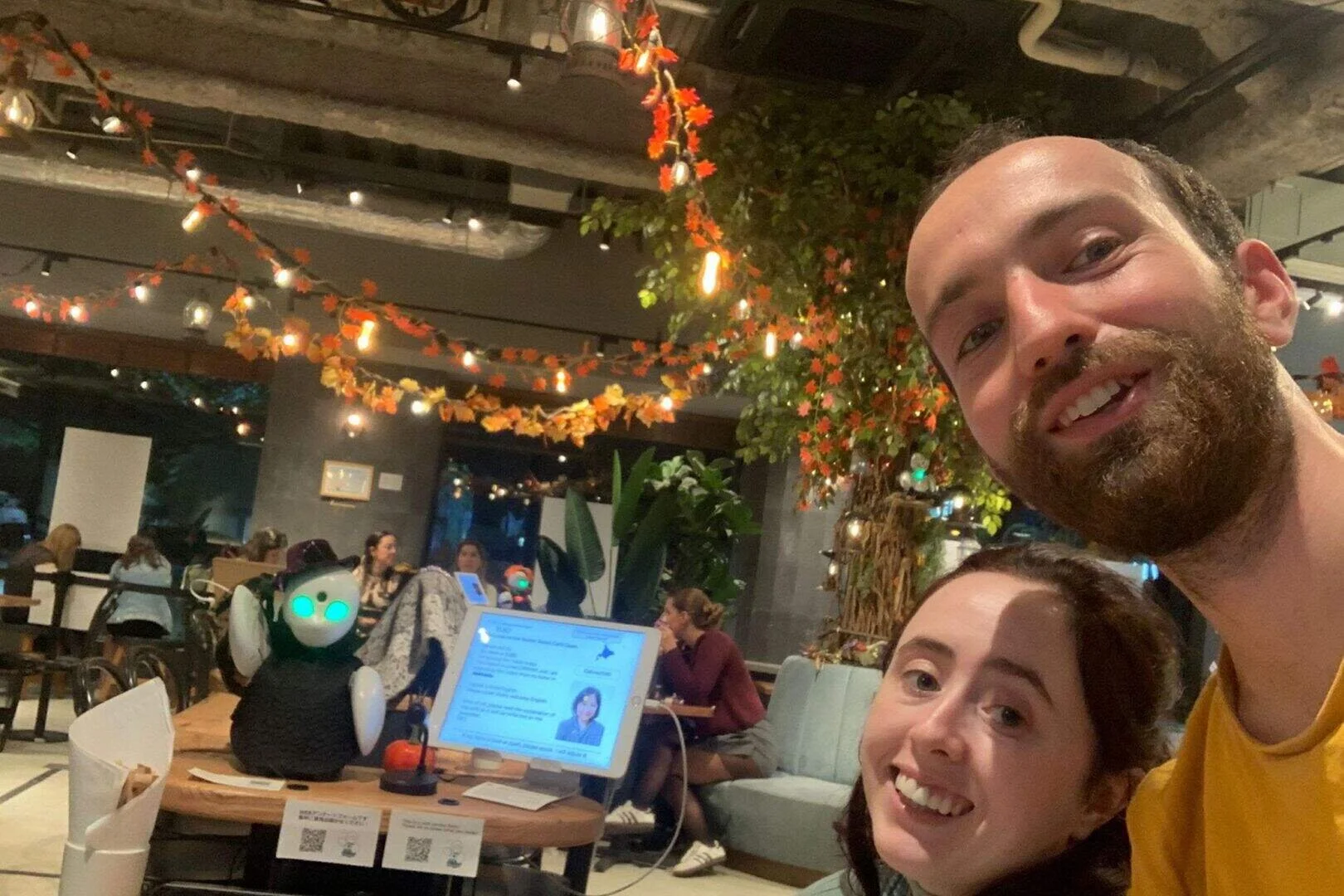 A couple posing and smiling with a small robot interface.