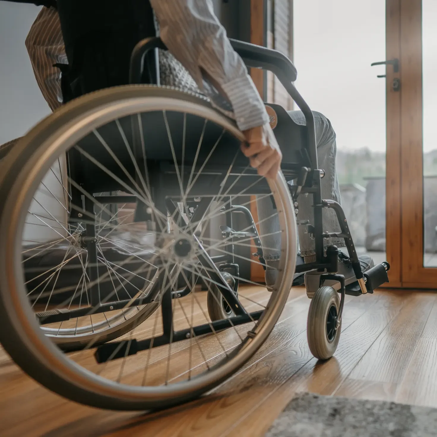 A wheelchair user with a disembodies hand resting on the wheel.