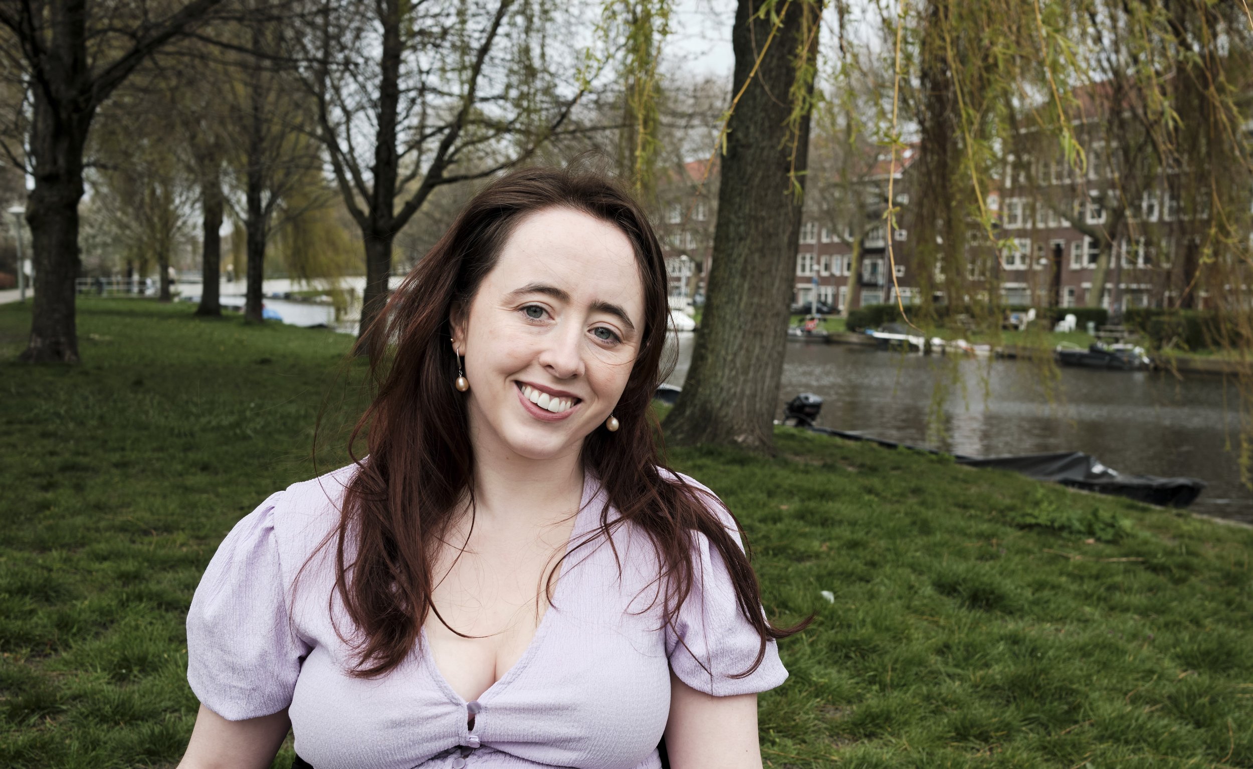 A woman (Niamh Ní Hoireabhaird) looking and smiling at the camera.