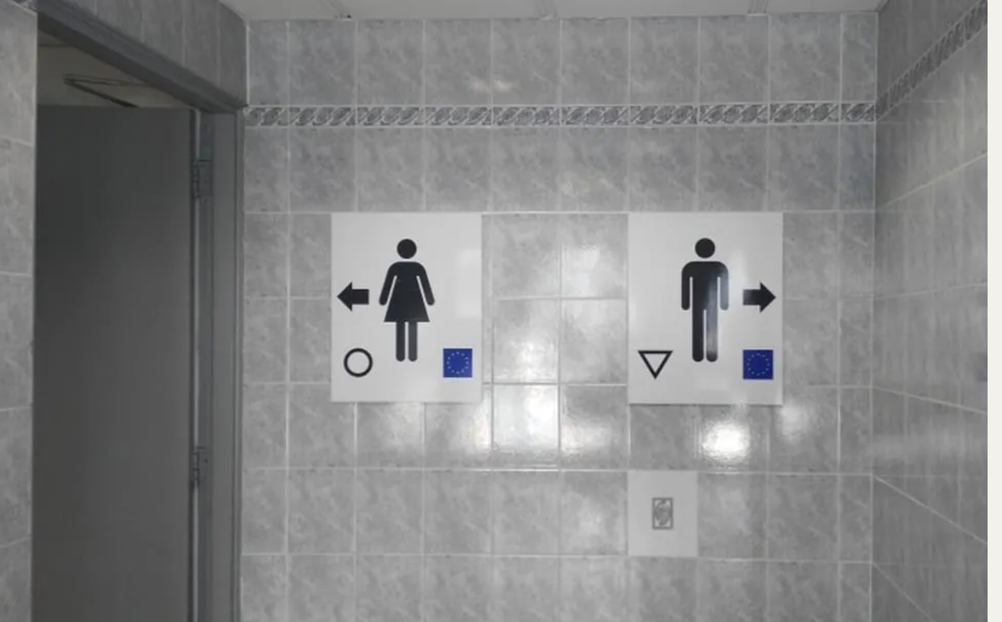 On a tiled wall, signs with a stick figure man and women pointing left and right.
