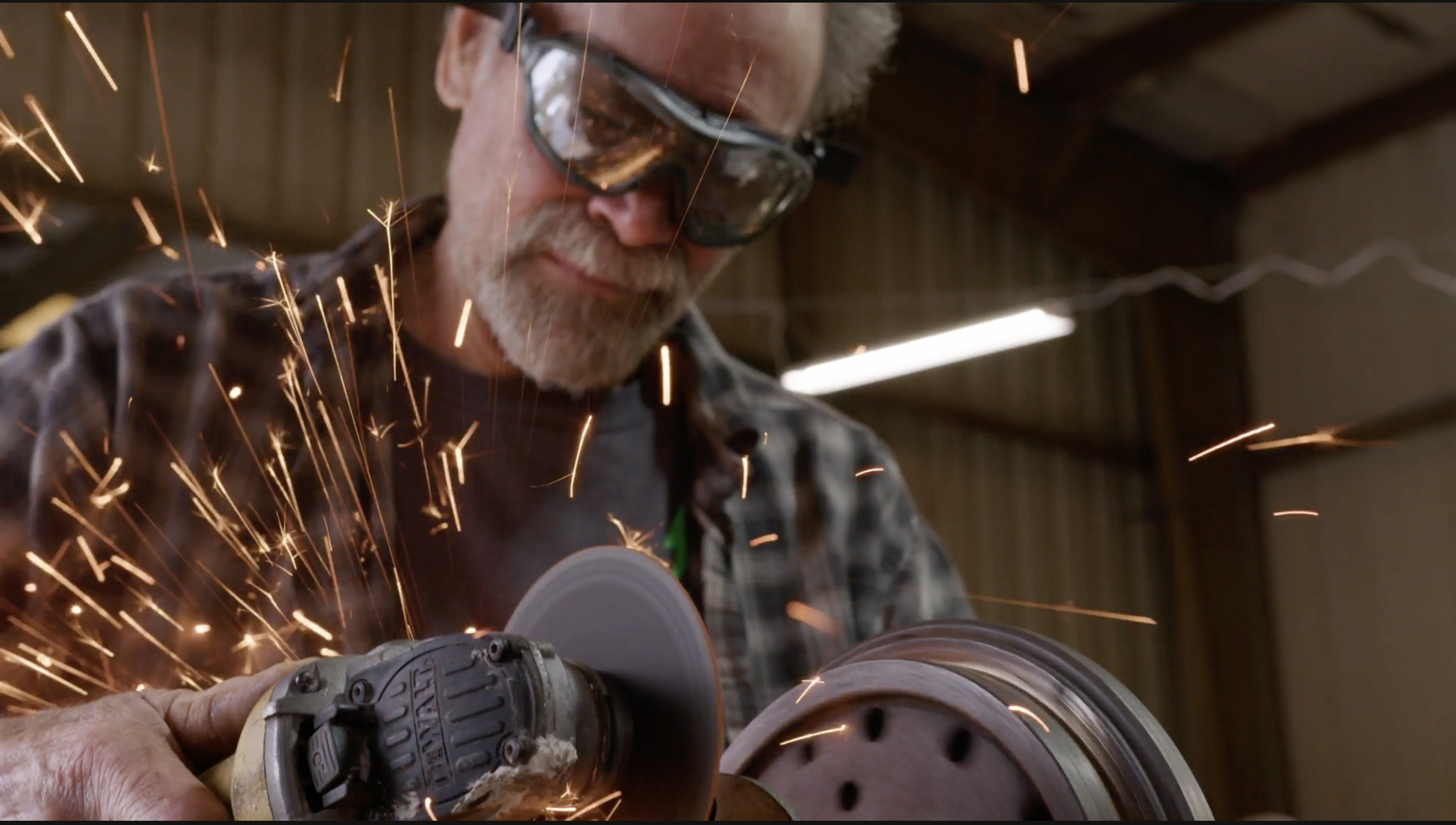 Steve Clunn cutting metal as sparks fly inside the Green Shed Conversions workshop.