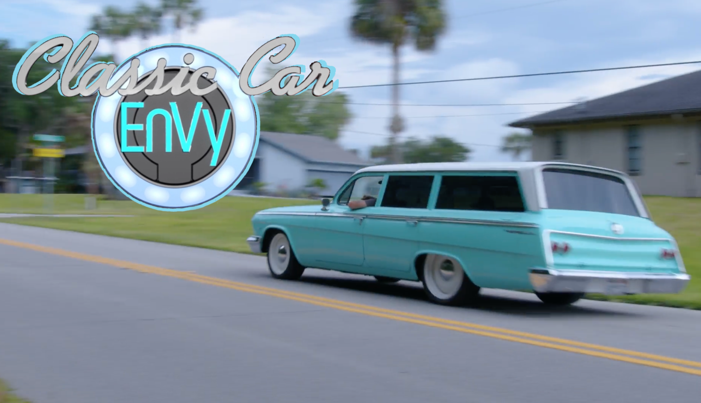 Turquoise vintage station wagon driving on the road with the Classic Car EnVy logo.