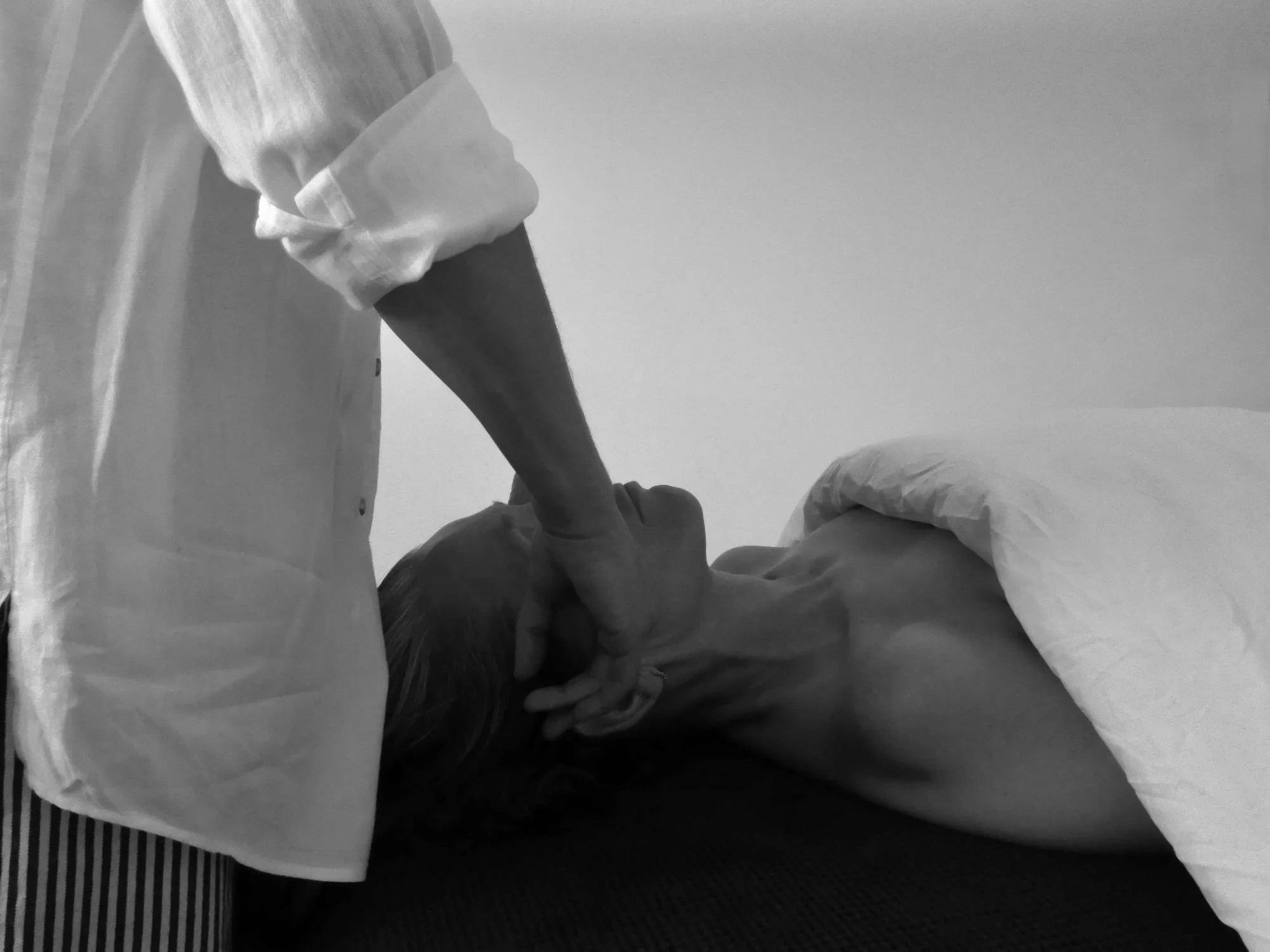 A nurse or doctor in scrubs and gloves administering a shot or injection to a patient lying down on a medical bed.
