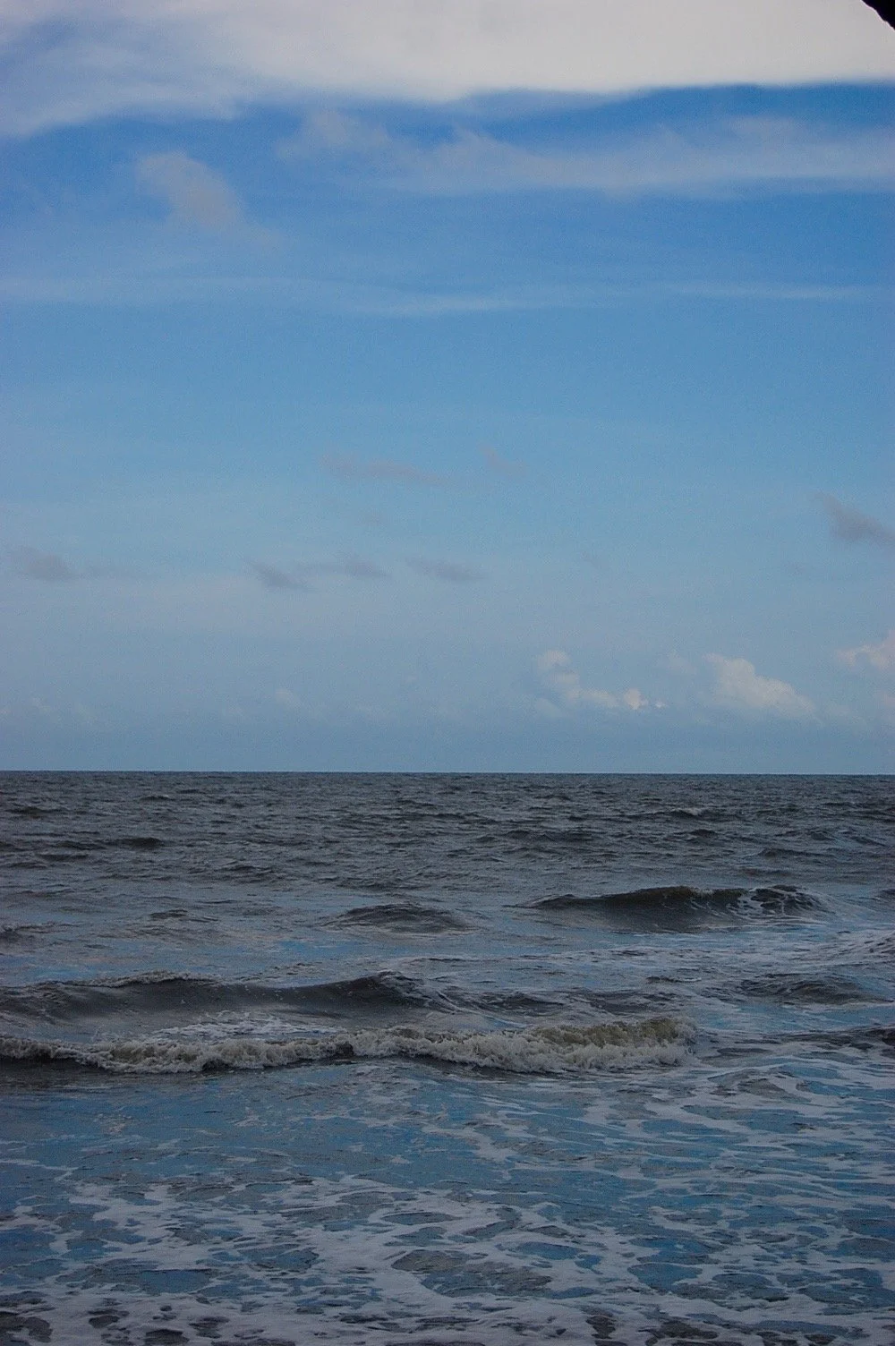 Ocean with waves and a partly cloudy sky.