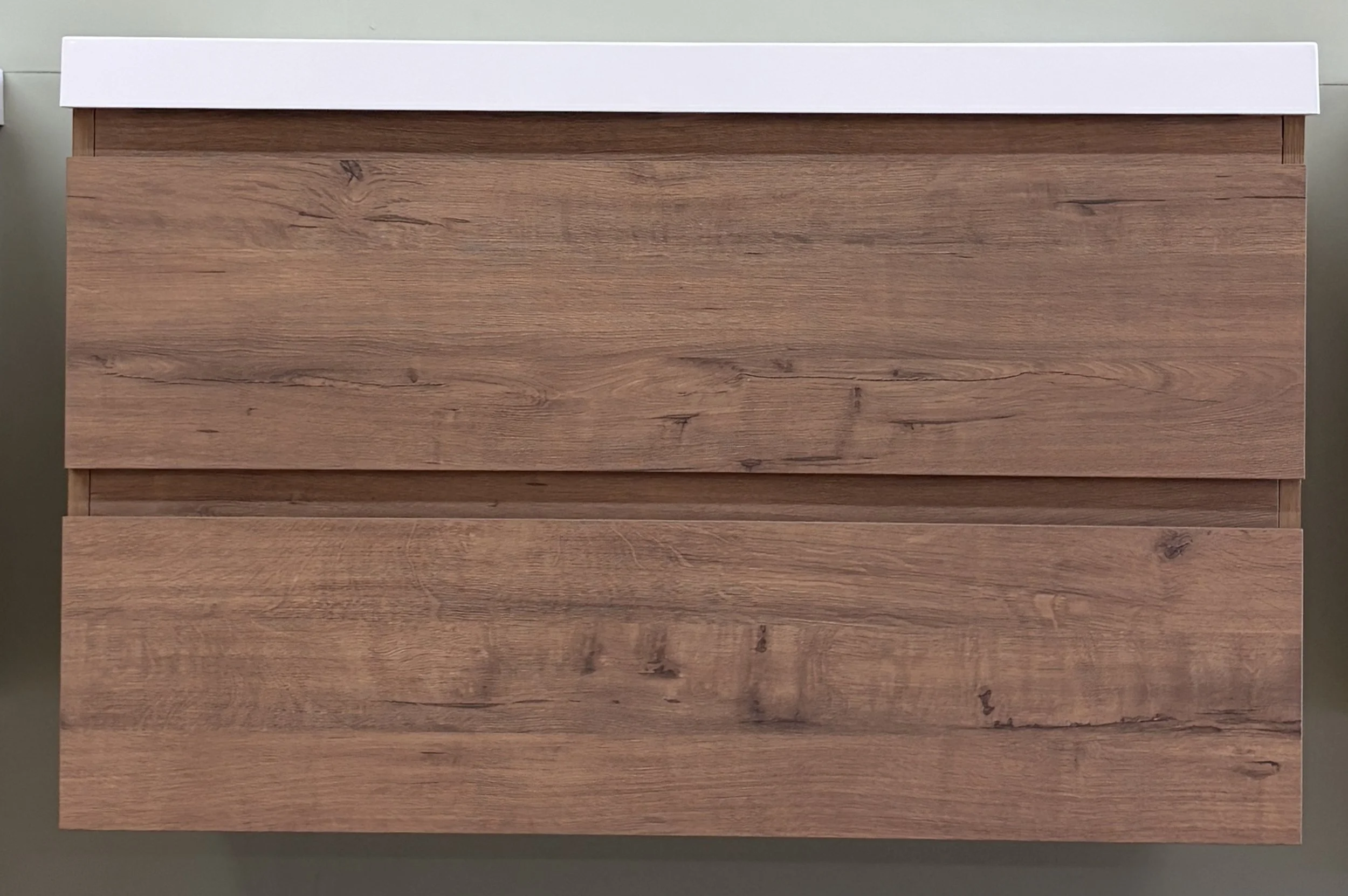 Photograph of a wooden dresser with a white top, set against a neutral background.