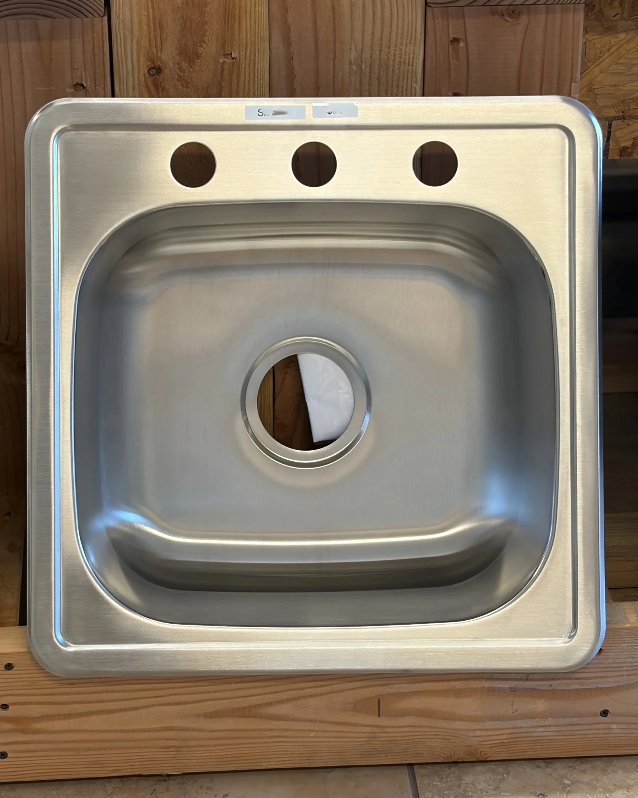 Stainless steel sink mounted on a wooden surface.