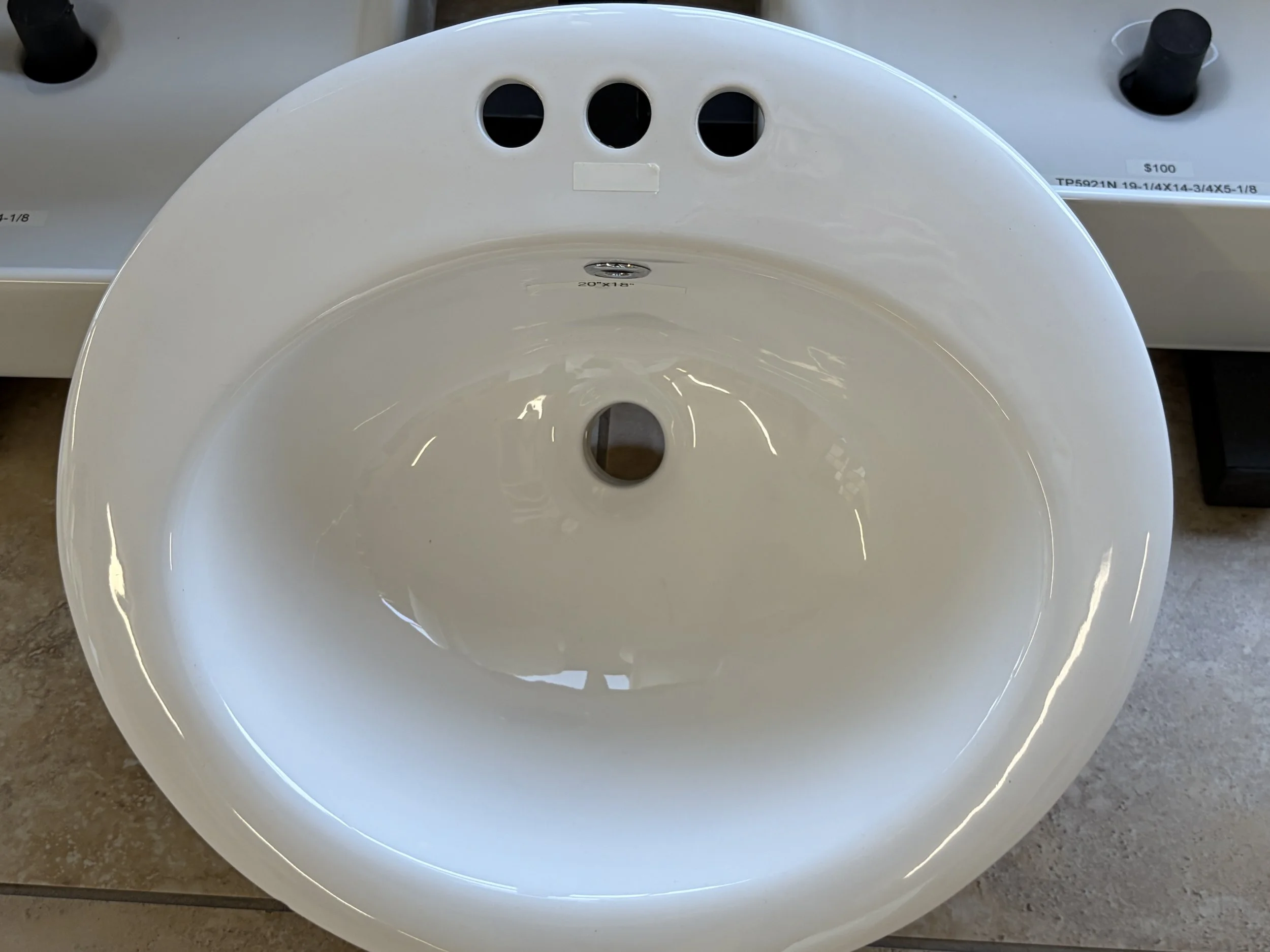 Close-up of a white toilet bowl viewed from above, with a label inside specifying its size as 20 inches by 18 inches.