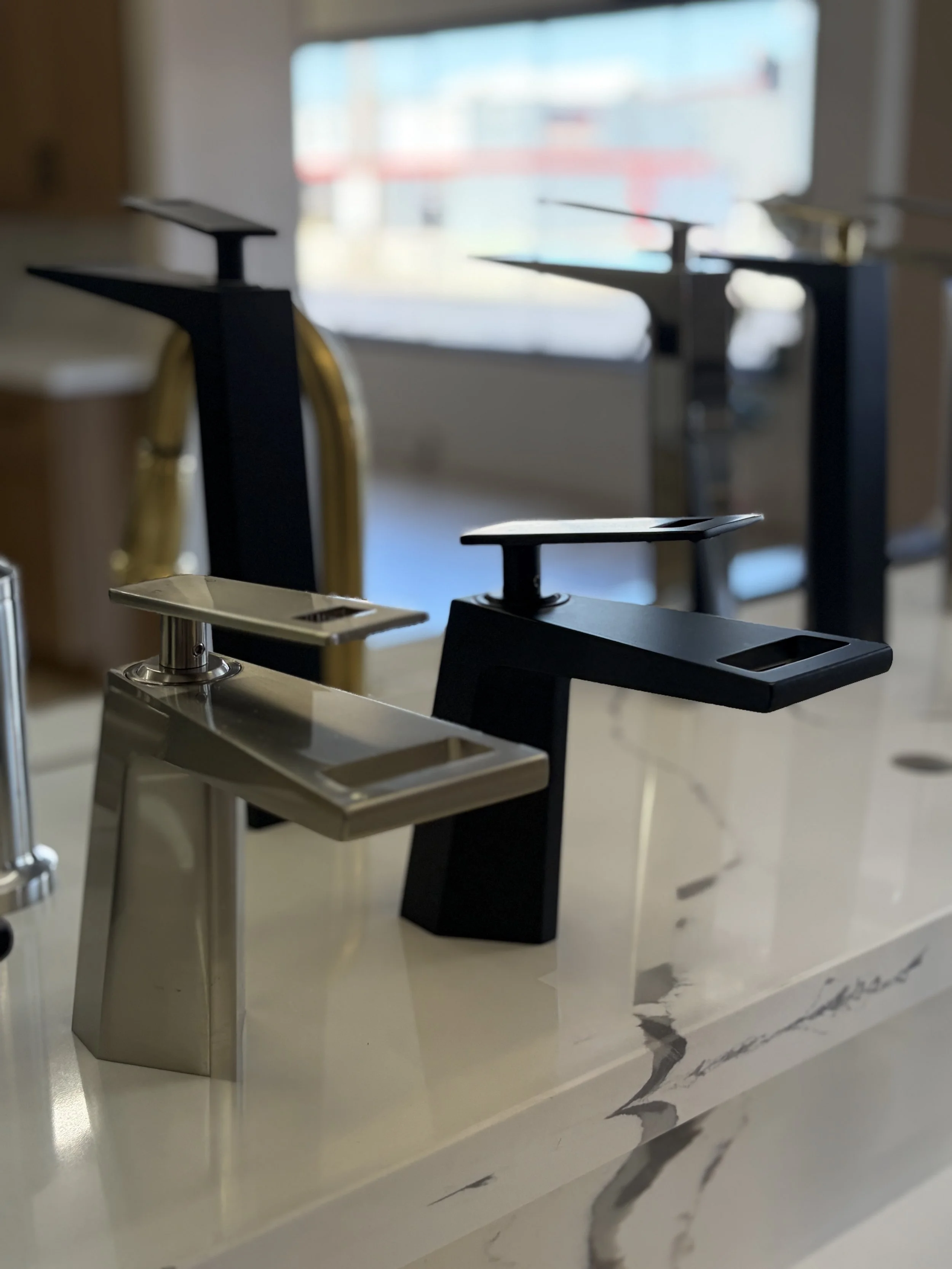 Close-up of black and metallic watch stands on a white marble surface with gray veining.