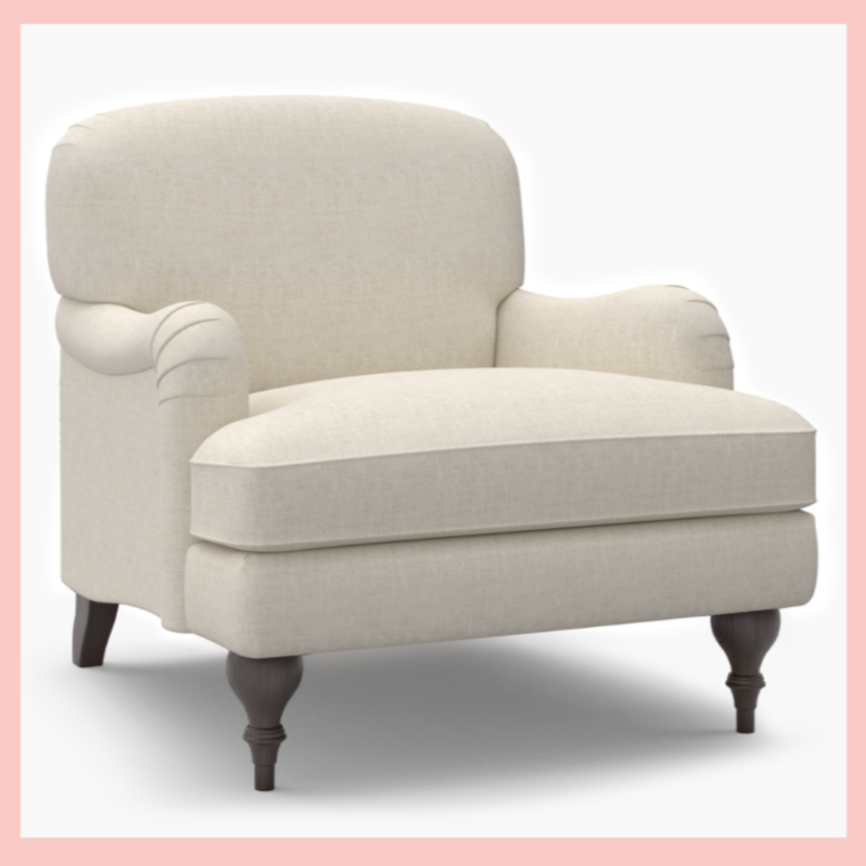 A beige upholstered armchair with dark wooden legs in a minimalist setting.