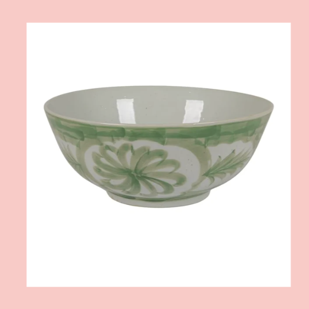 A ceramic bowl with green floral and leaf designs on a white background.