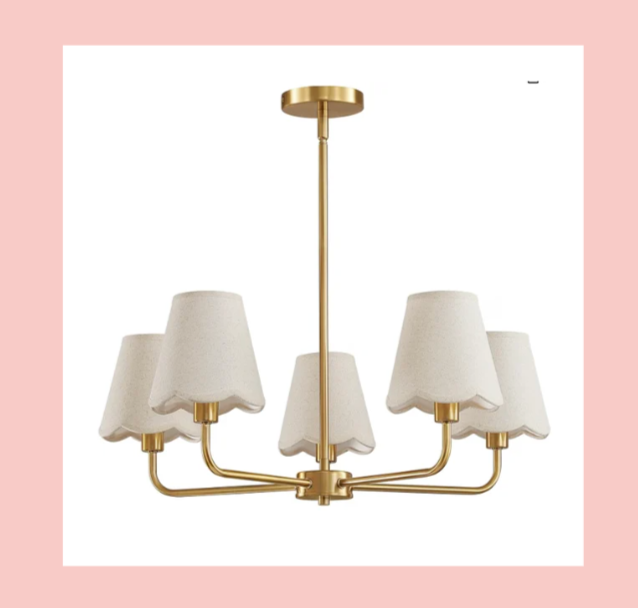 A modern chandelier with a gold finish and six white lampshades suspended from curved arms.
