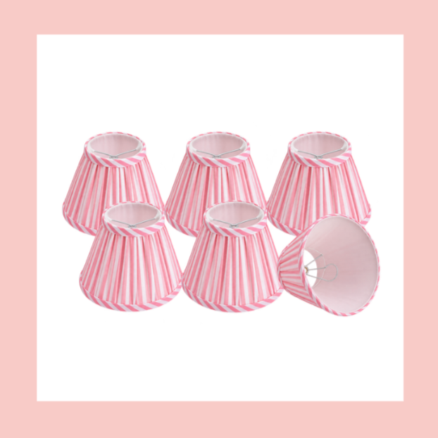 Six pink and white striped lampshades arranged in a group, with one lampshade laid on its side showing the interior and wire frame.