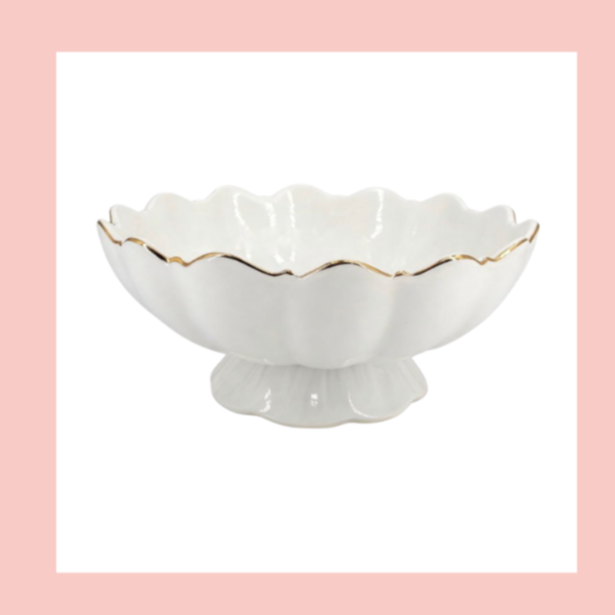 White ceramic bowl with a scalloped edge and gold trim, on a pink and white background.