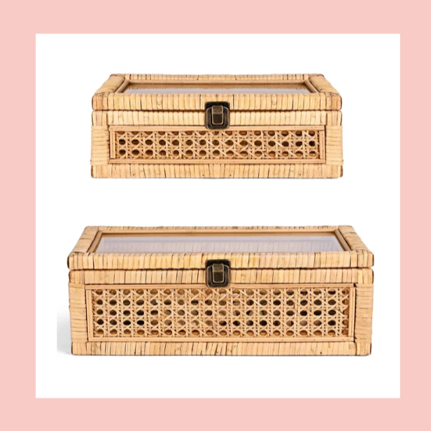 Two rectangular rattan storage boxes with glass tops and black latch closures, stacked one above the other, on a pink background.