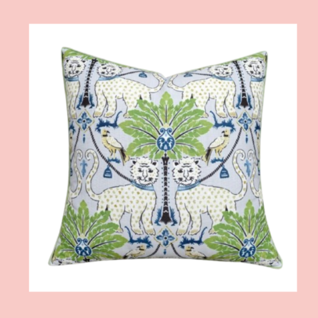 Decorative square pillow featuring a pattern of lions, tigers, and birds with green foliage on a light background.