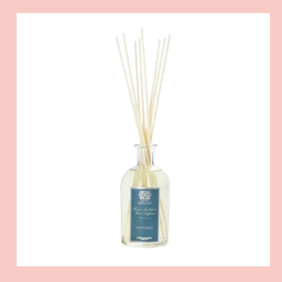 A reed diffuser with white reed sticks in a clear glass bottle with a blue label.