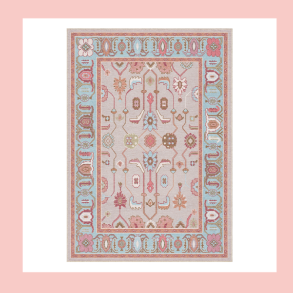 A decorative area rug with a floral and geometric pattern in pastel colors, surrounded by a pink border.