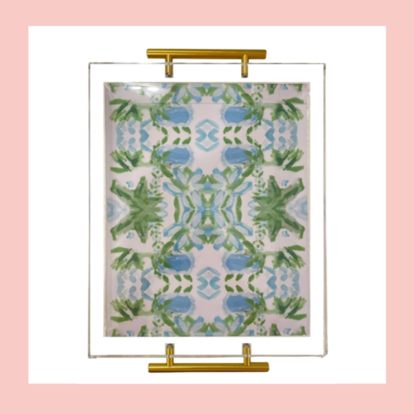 Mirror with a patterned fabric or paper backing featuring green and blue abstract leaf and geometric designs, mounted with gold hardware.