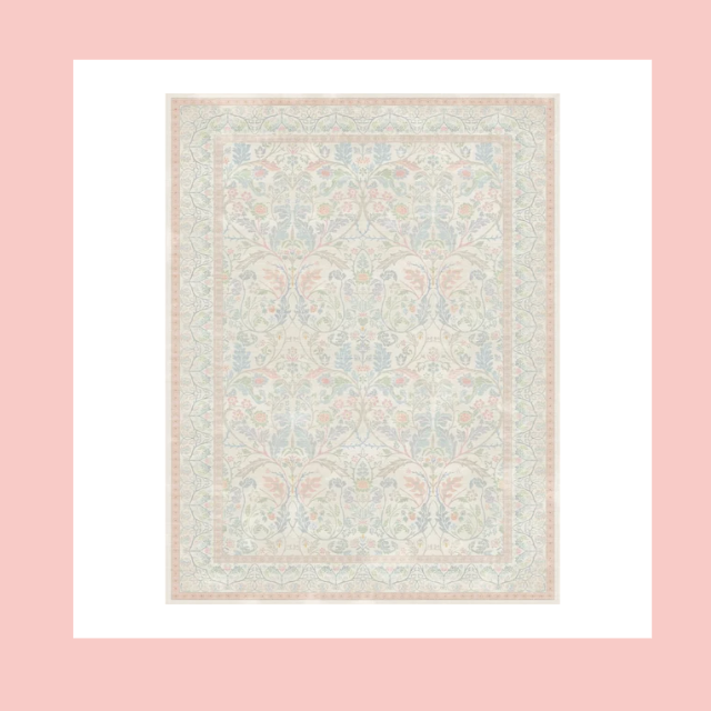 A light-colored, intricate patterned rug with floral and geometric designs, placed on a pink background.