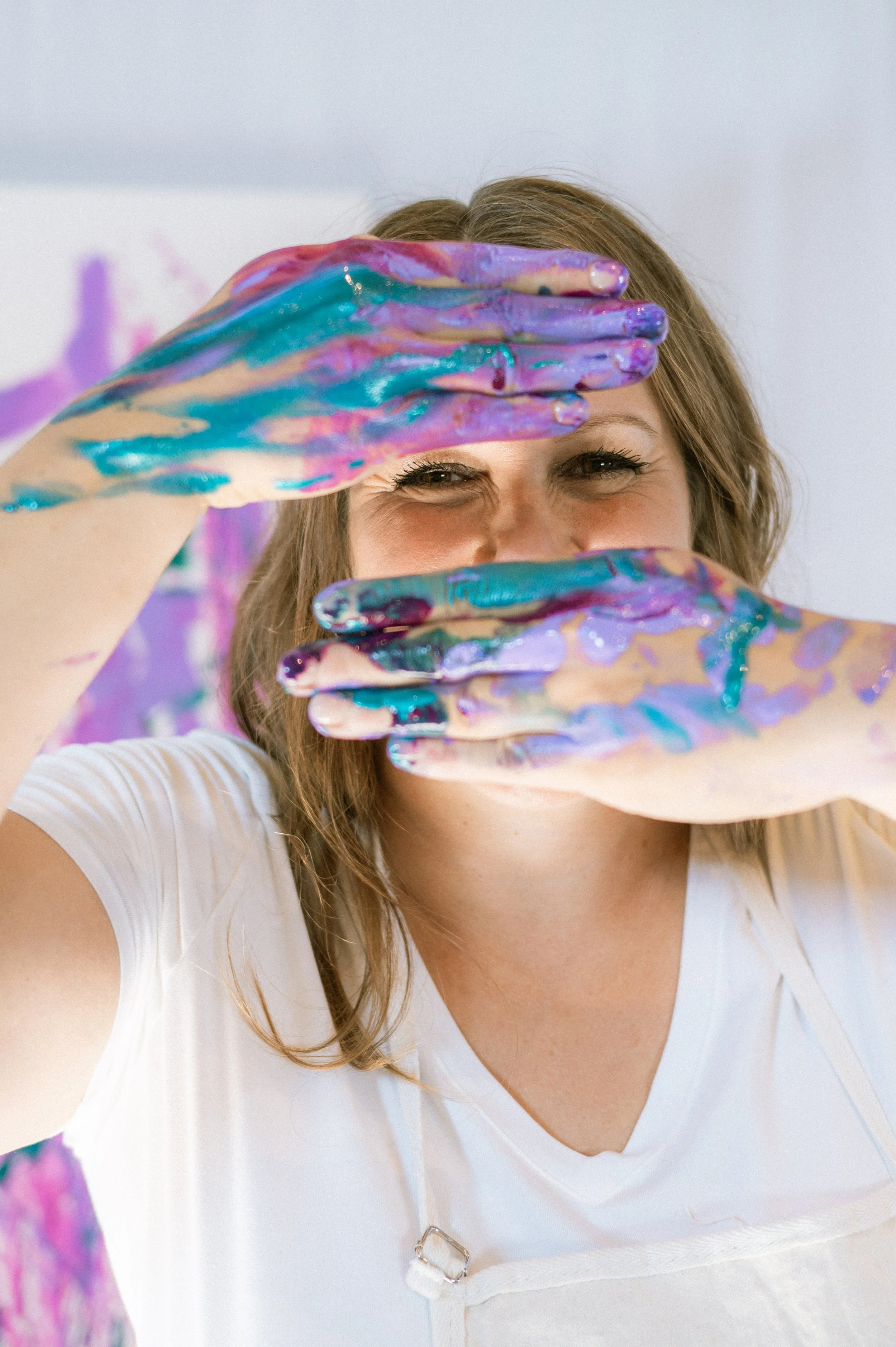 Holly Lothian has paint on her hands and she's holding them up in front of her face.