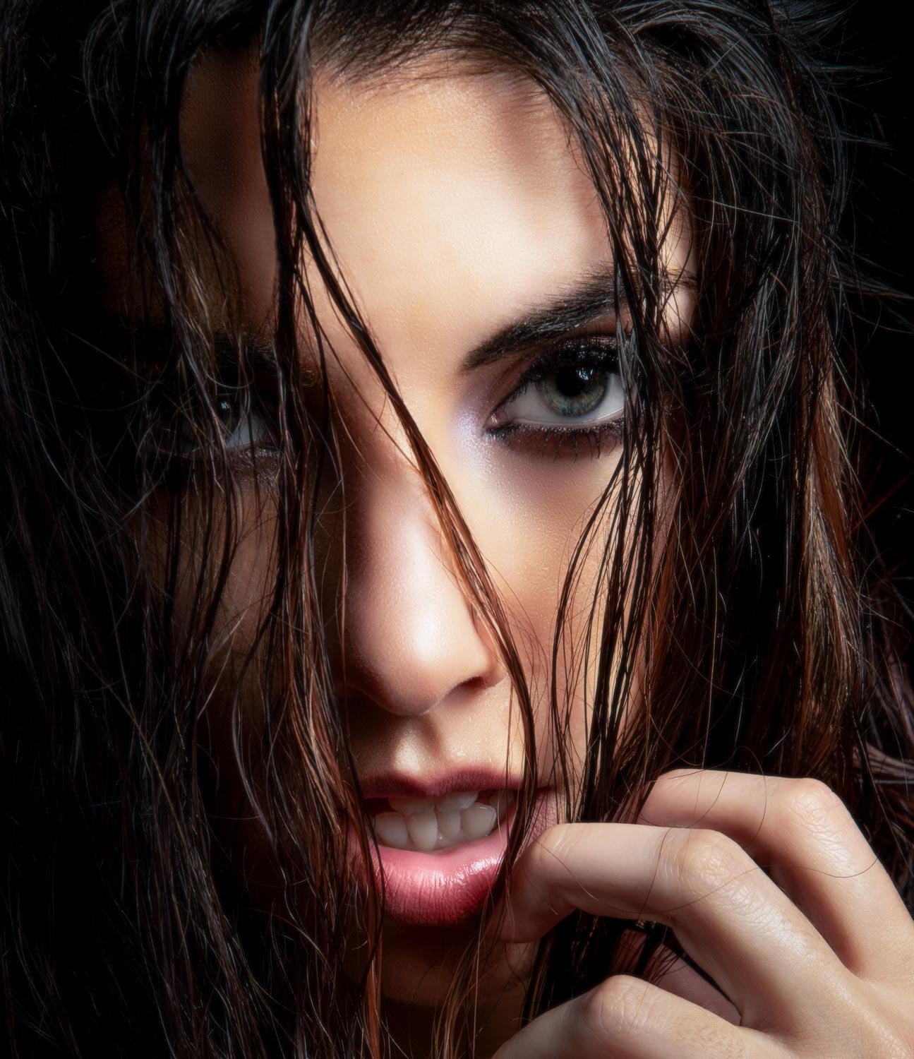 Close-up of a woman with wet hair, piercing green eyes, and a slightly open mouth, looking intensely at the camera.