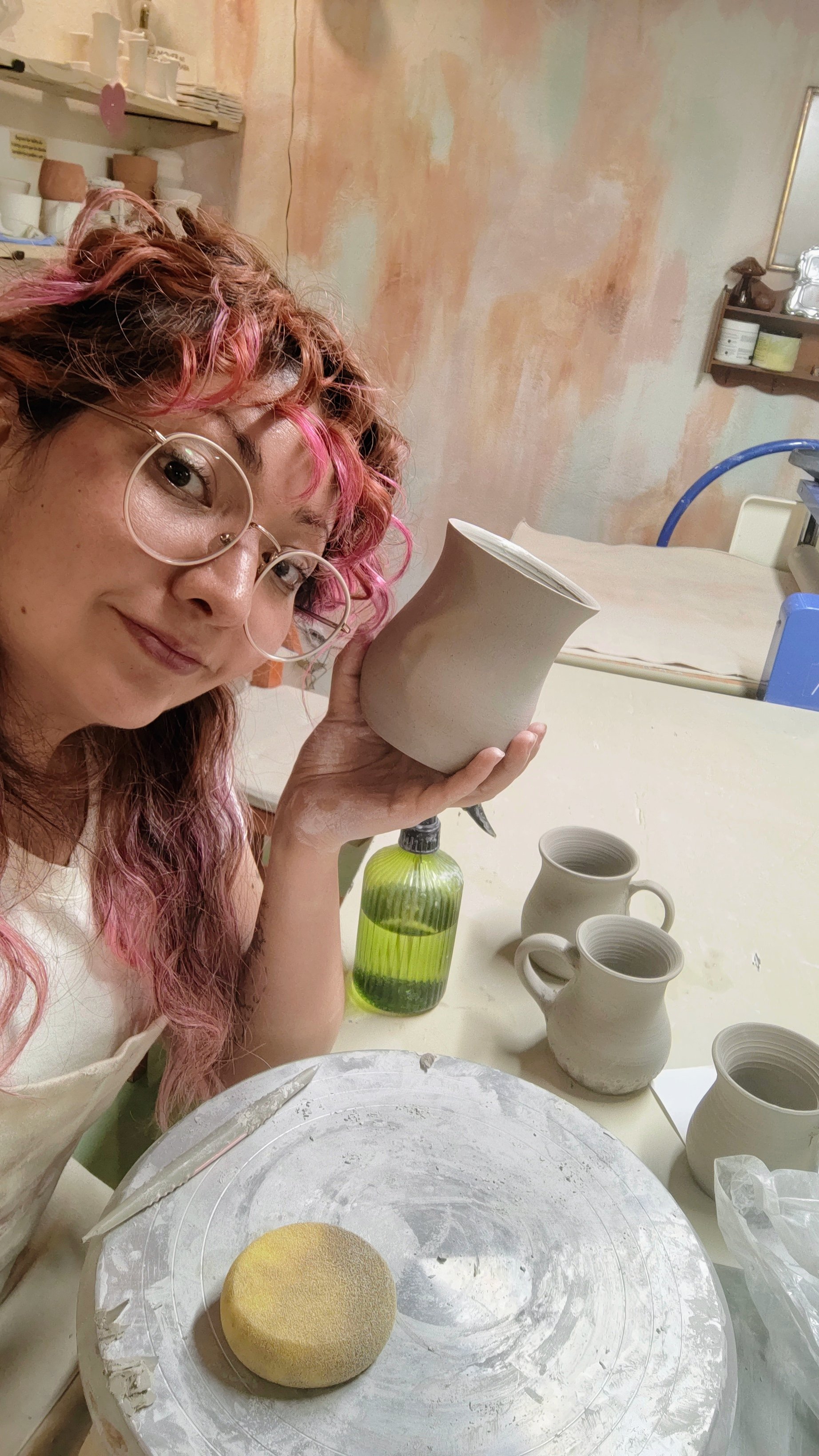 Mexican artist a pot in a pottery studio surrounded by ceramic items and tools.