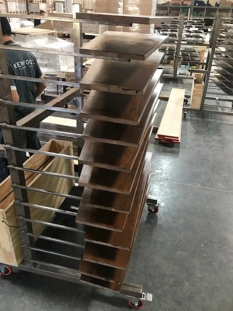 Stacks of wooden boards in a workshop or warehouse setting.
