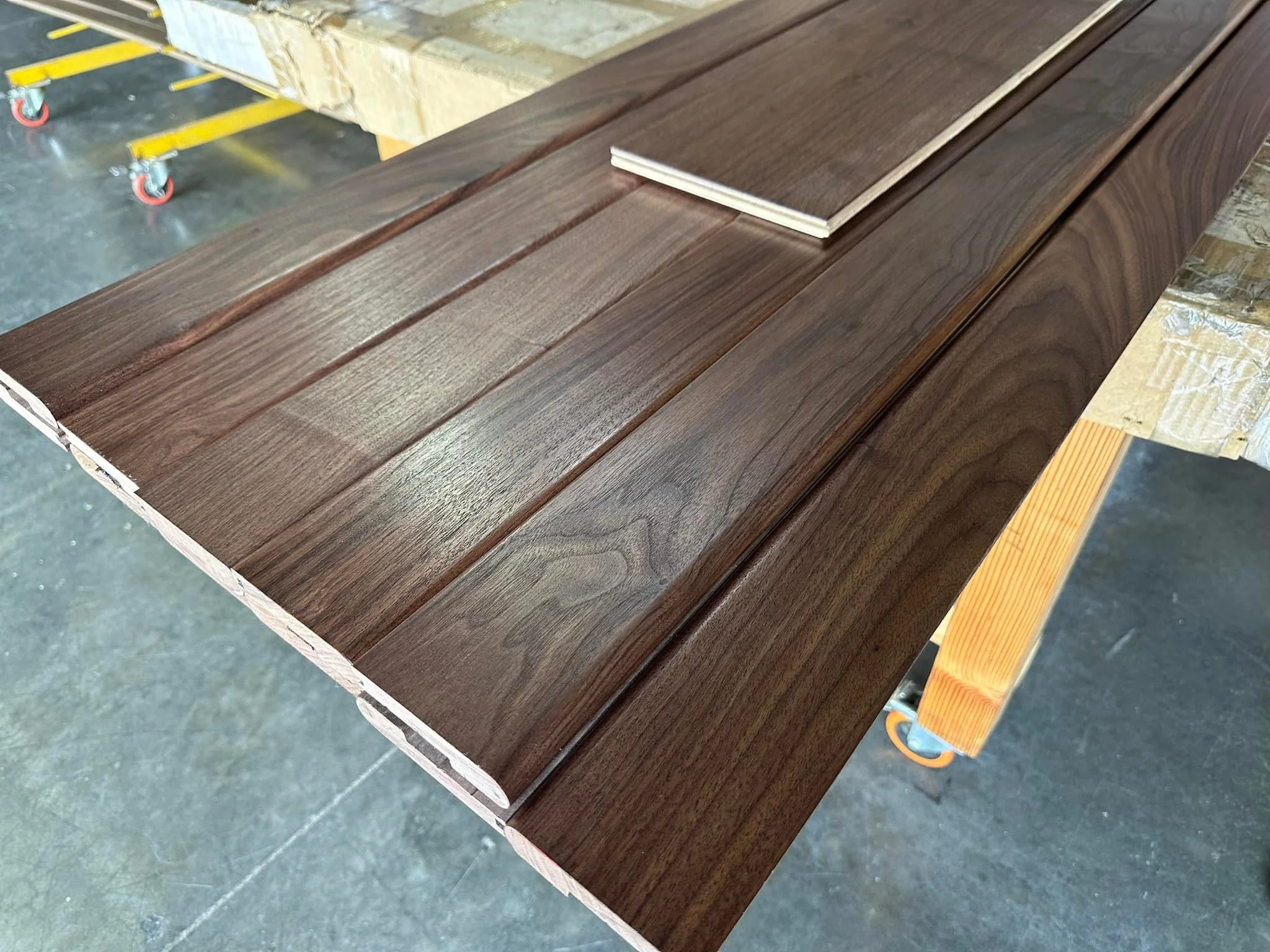 Piles of wooden planks on a worktable in a workshop.