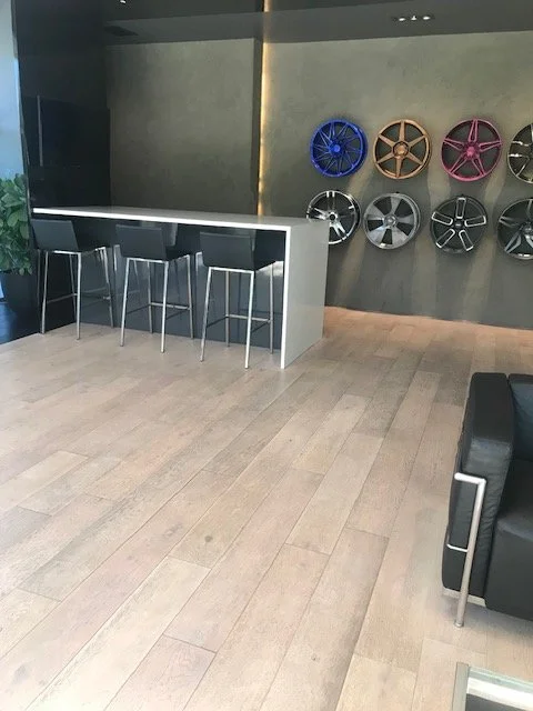 Modern room with a bar-height counter, four black bar stools, and a wall displaying various colorful car rims.