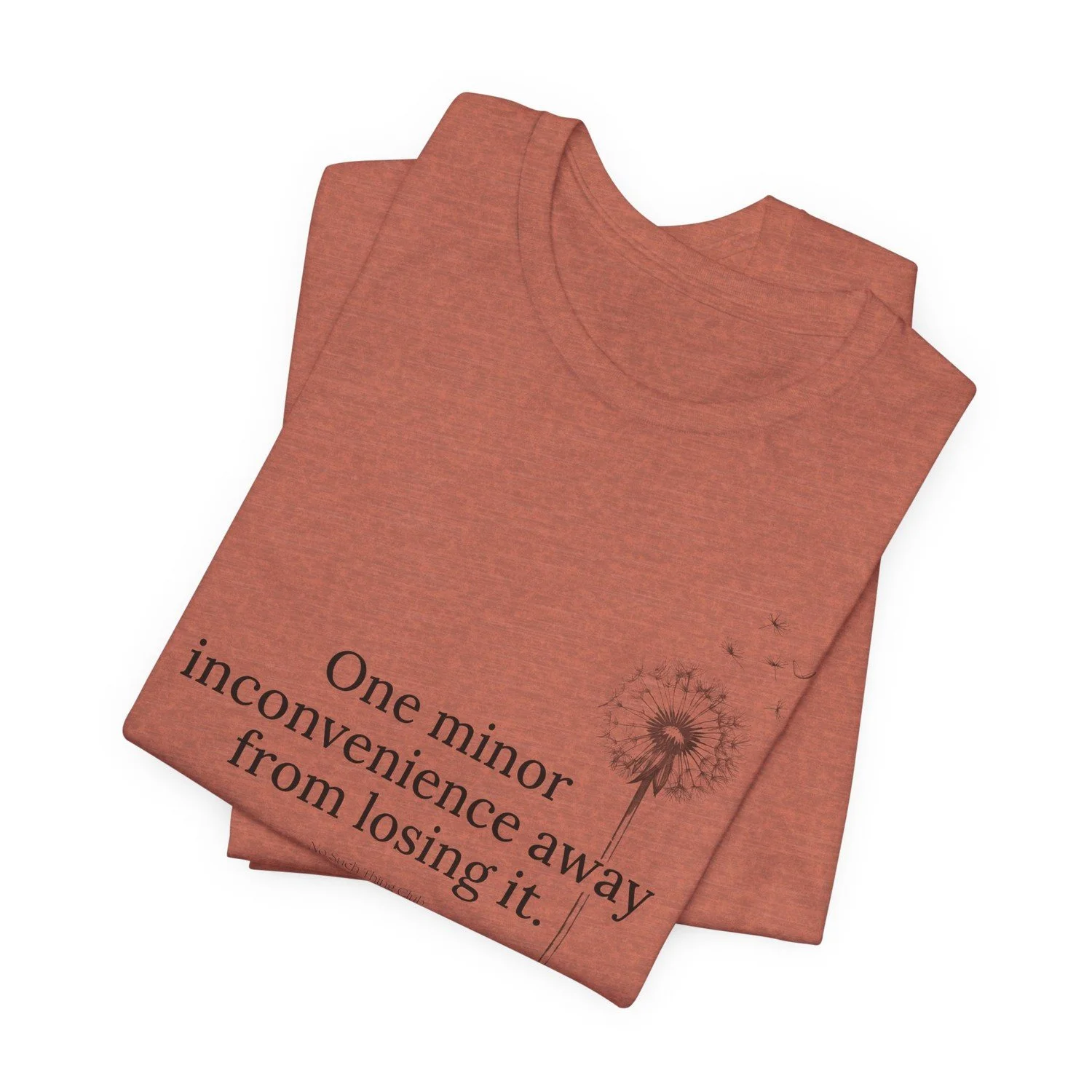 The One Minor Inconvenience tee folded, showing the black print and the dandelion