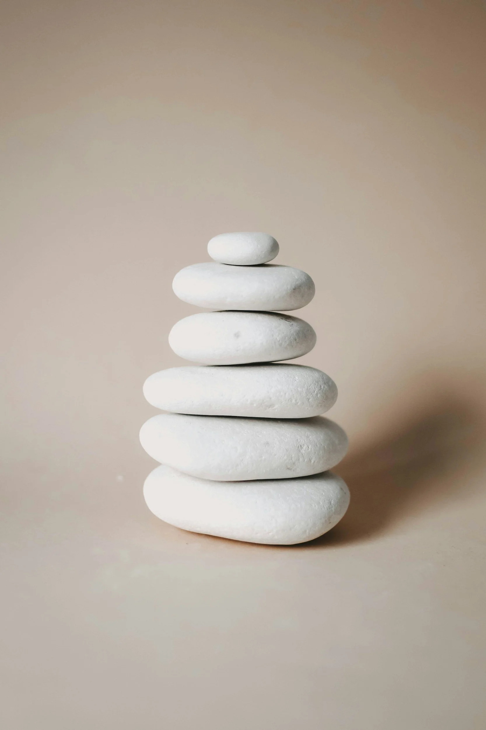 Stacked white stones forming a balanced tower against a neutral background.