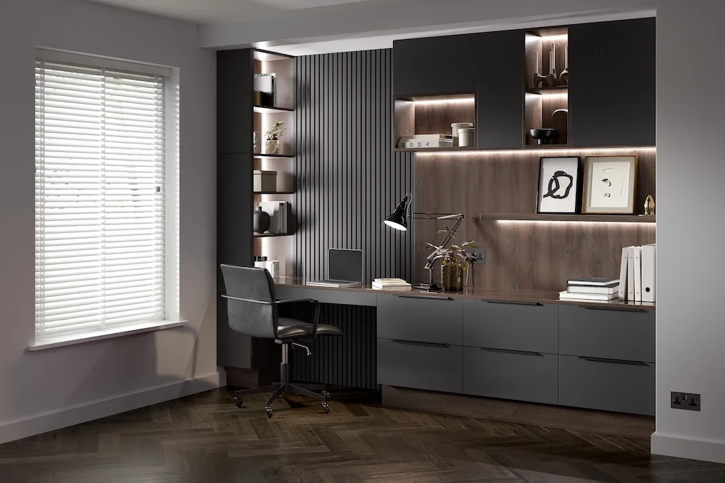 Modern home office with a textured wall, built-in shelves, and a desk with a black chair.