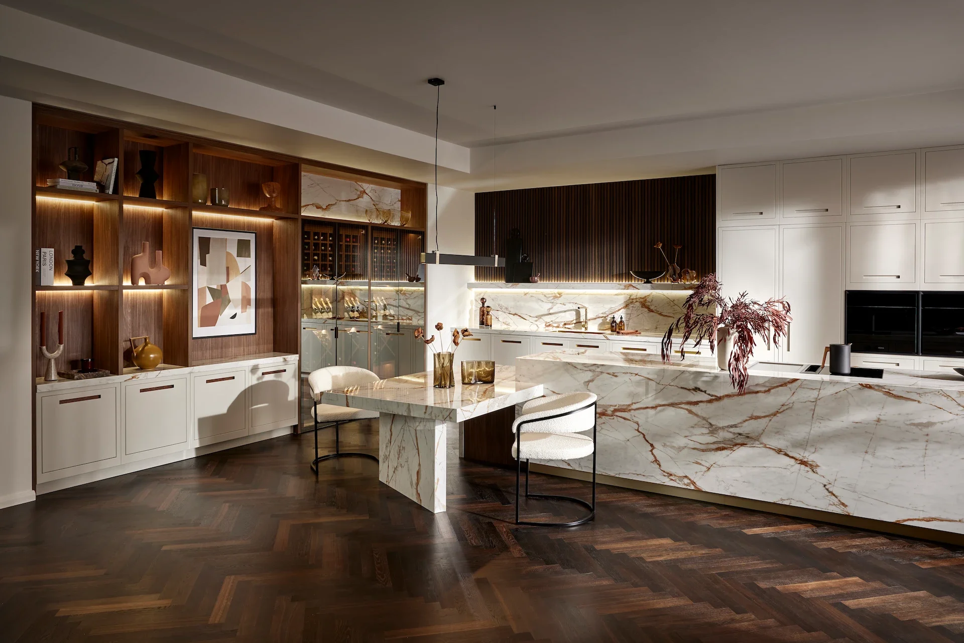 Modern kitchen with white and dark wood cabinetry, marble countertops, and a marble island. Decor includes abstract wall art, vases, and decorative objects, with dark wooden flooring.