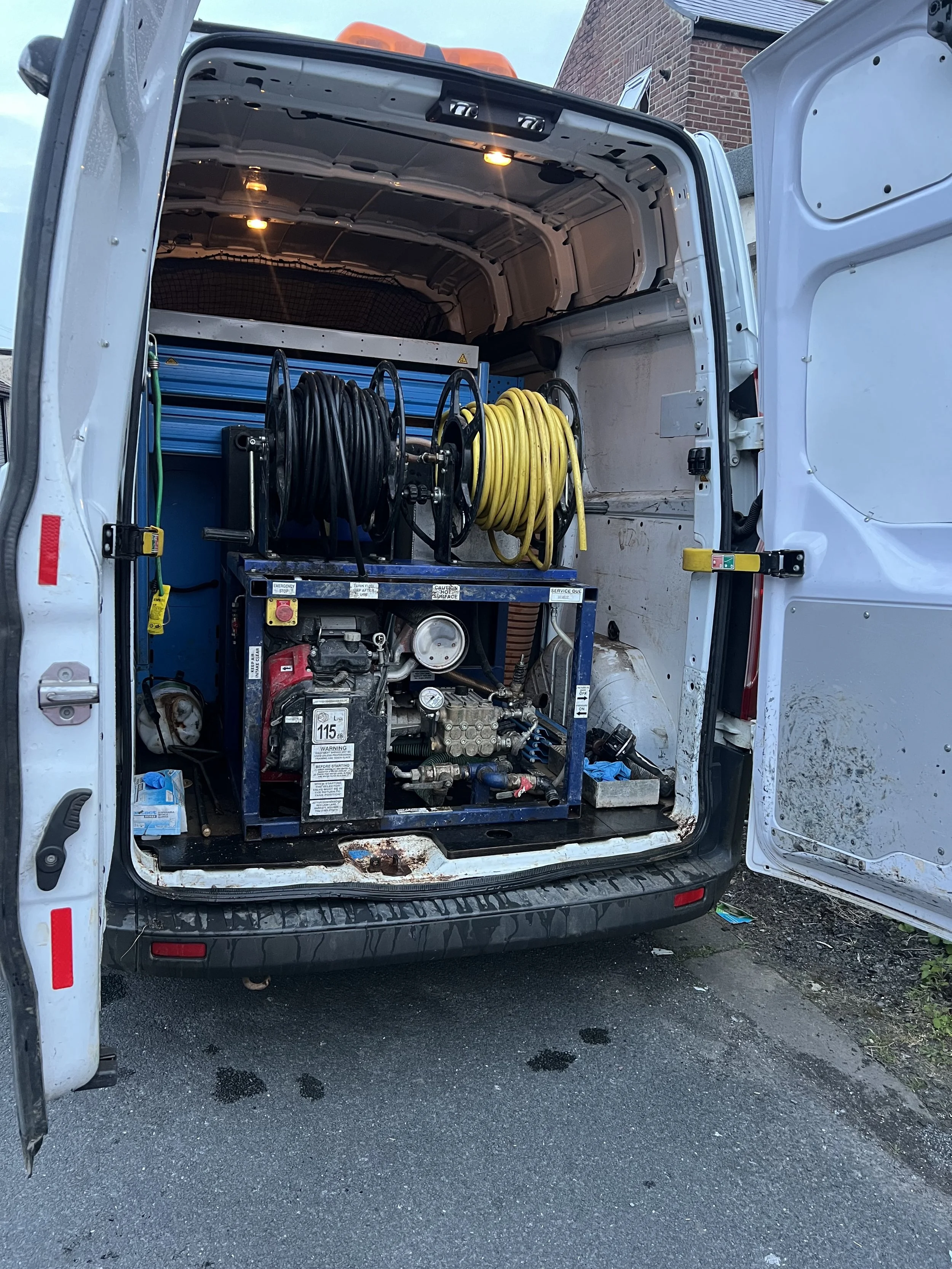 Back of a work van with tools, hoses, and equipment inside.