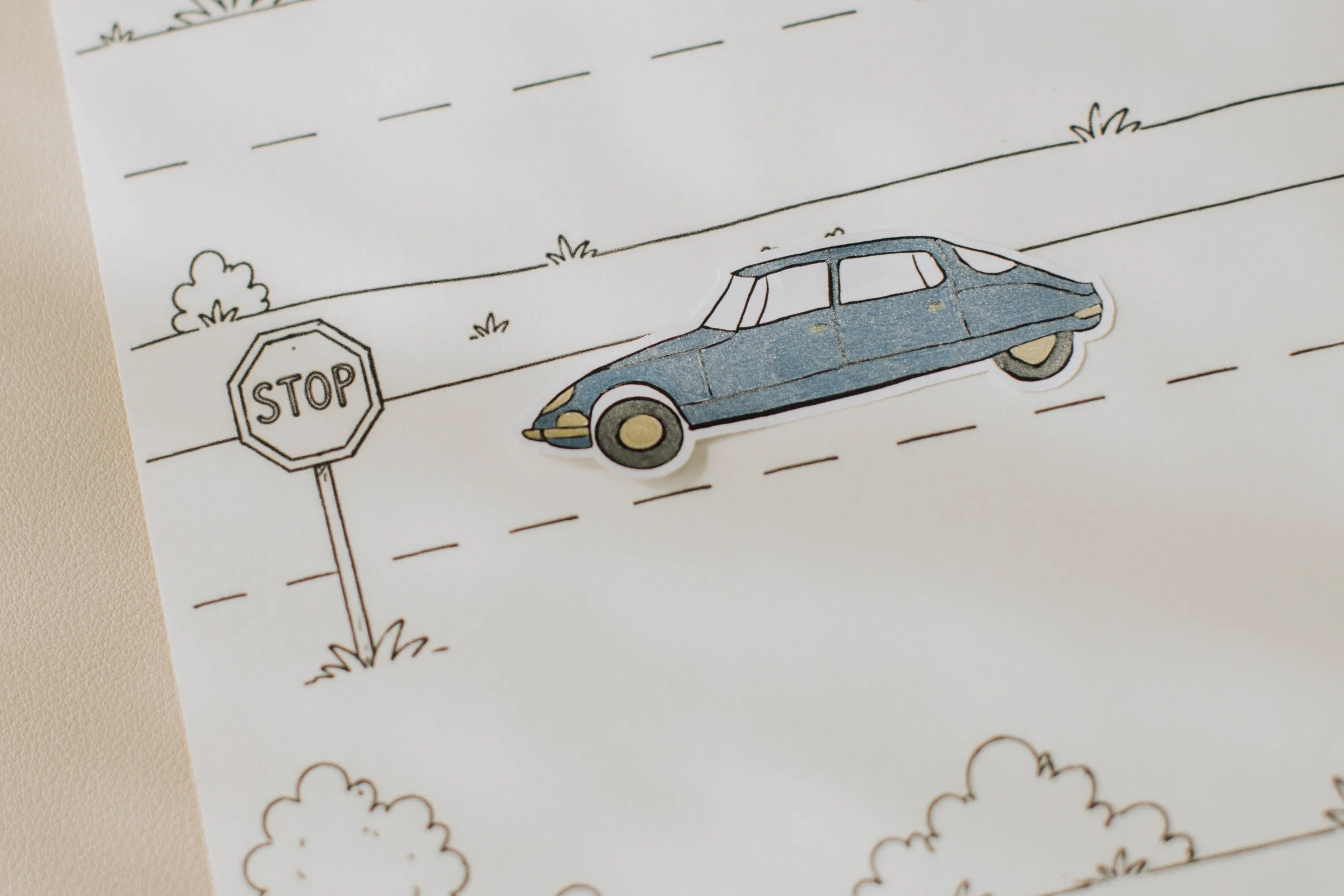 Colored car stickers arranged on a hand-drawn road scene.