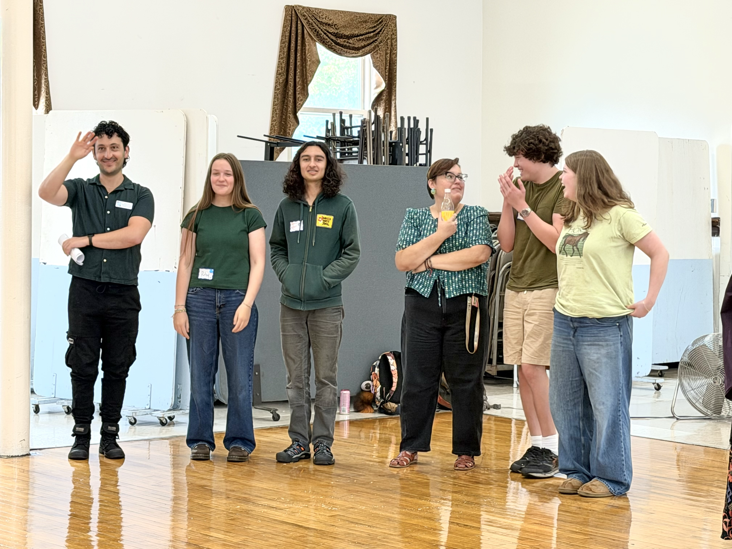 Group of students and teachers standing together and talking, all in green shirts.
