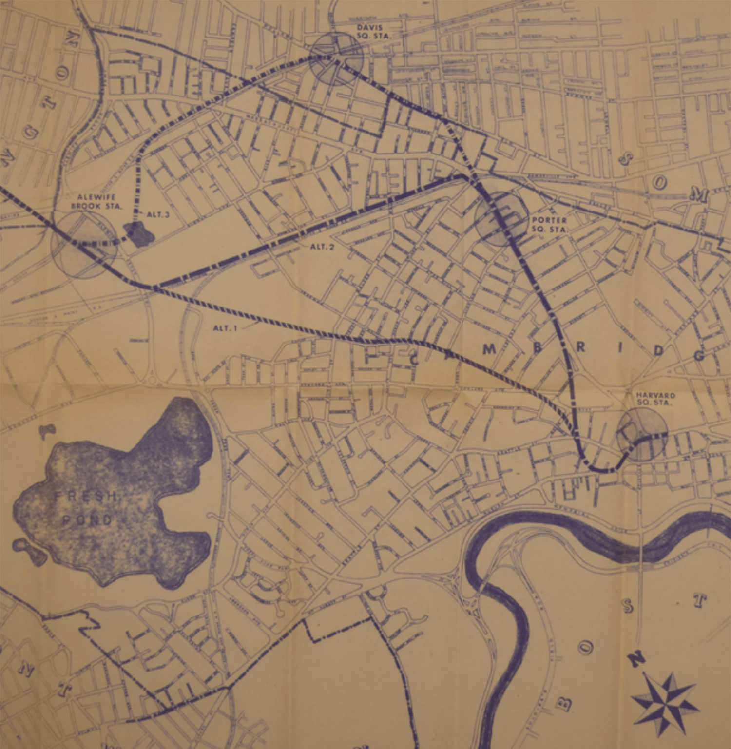 Map of a city showing subway routes, stations, parks, and a river with a compass rose.