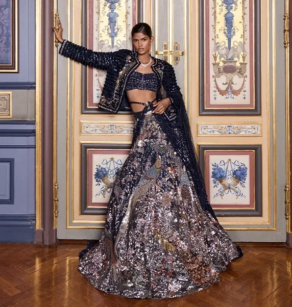 Woman in a sequined black and silver outfit posing in front of ornate double doors with floral and gold accents.