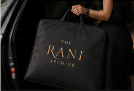 A person holding a large black bag with gold lettering that says "The Rani Archive".