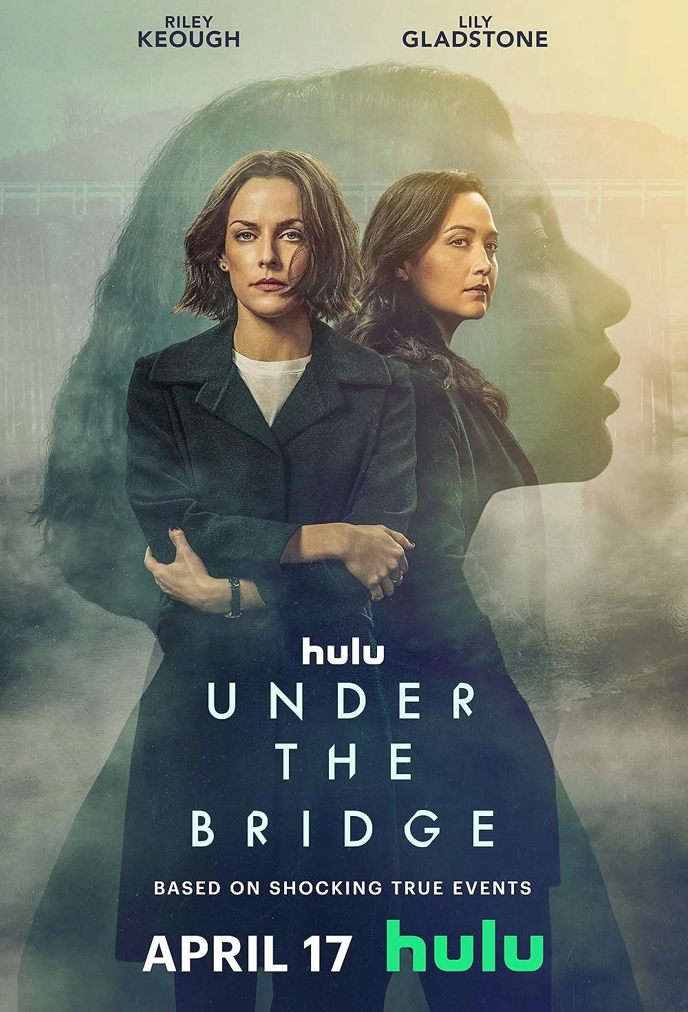 Poster for the series "Under the Bridge" featuring two women standing back-to-back, with ghostly images of a bridge and mountain in the background. The names Riley Keough and Lily Gladstone are at the top. The series is available on Hulu starting Apr