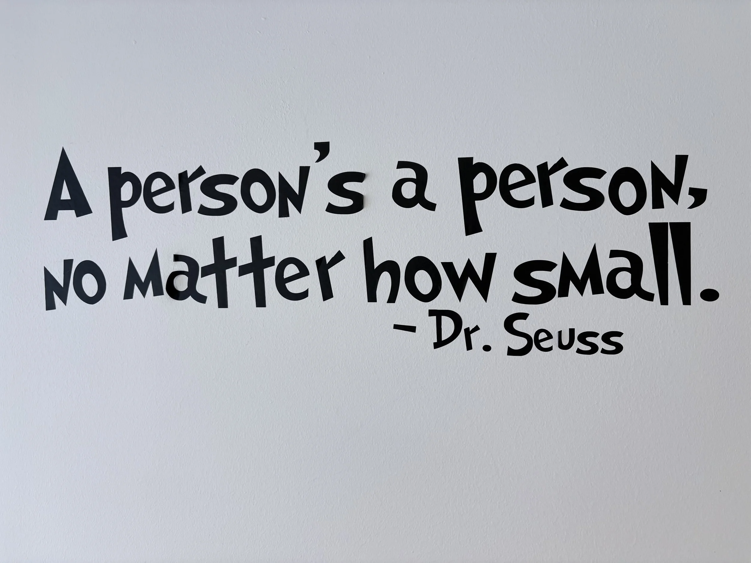 Close-up of a quote by Dr. Seuss printed on a wall, which reads, "A person's a person, no matter how small."