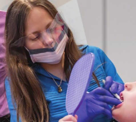 Dental hygienist examining a patient's mouth at a dental clinic.