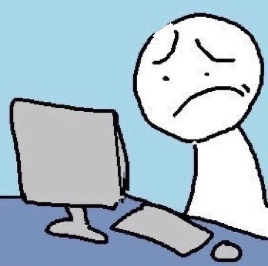 A cartoon person with a sad facial expression sitting at a desk with a computer, keyboard, and mouse.