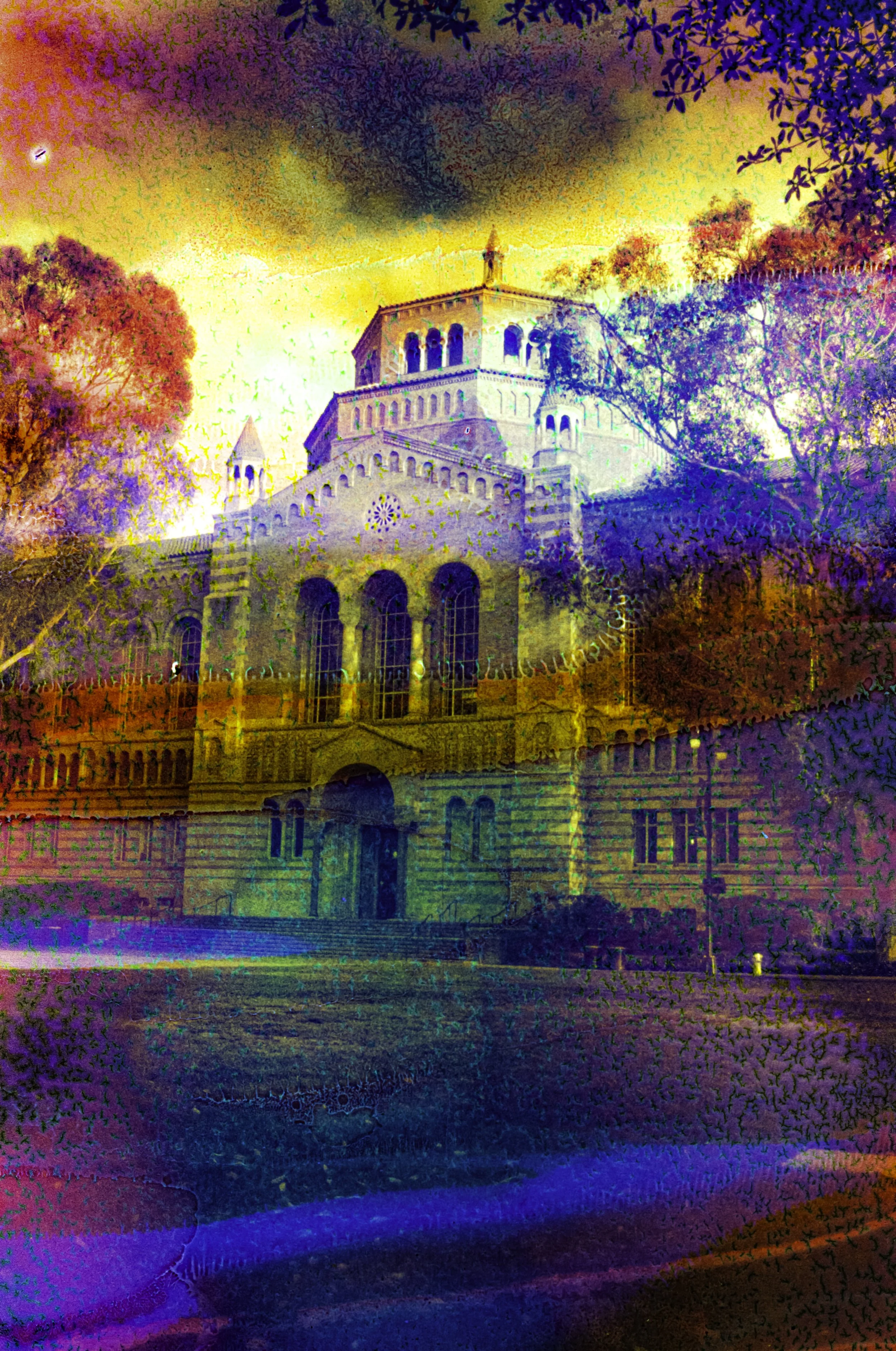 Powell Library at UCLA surrounded by trees beneath a chemically altered yellow, blue, and orange sky.