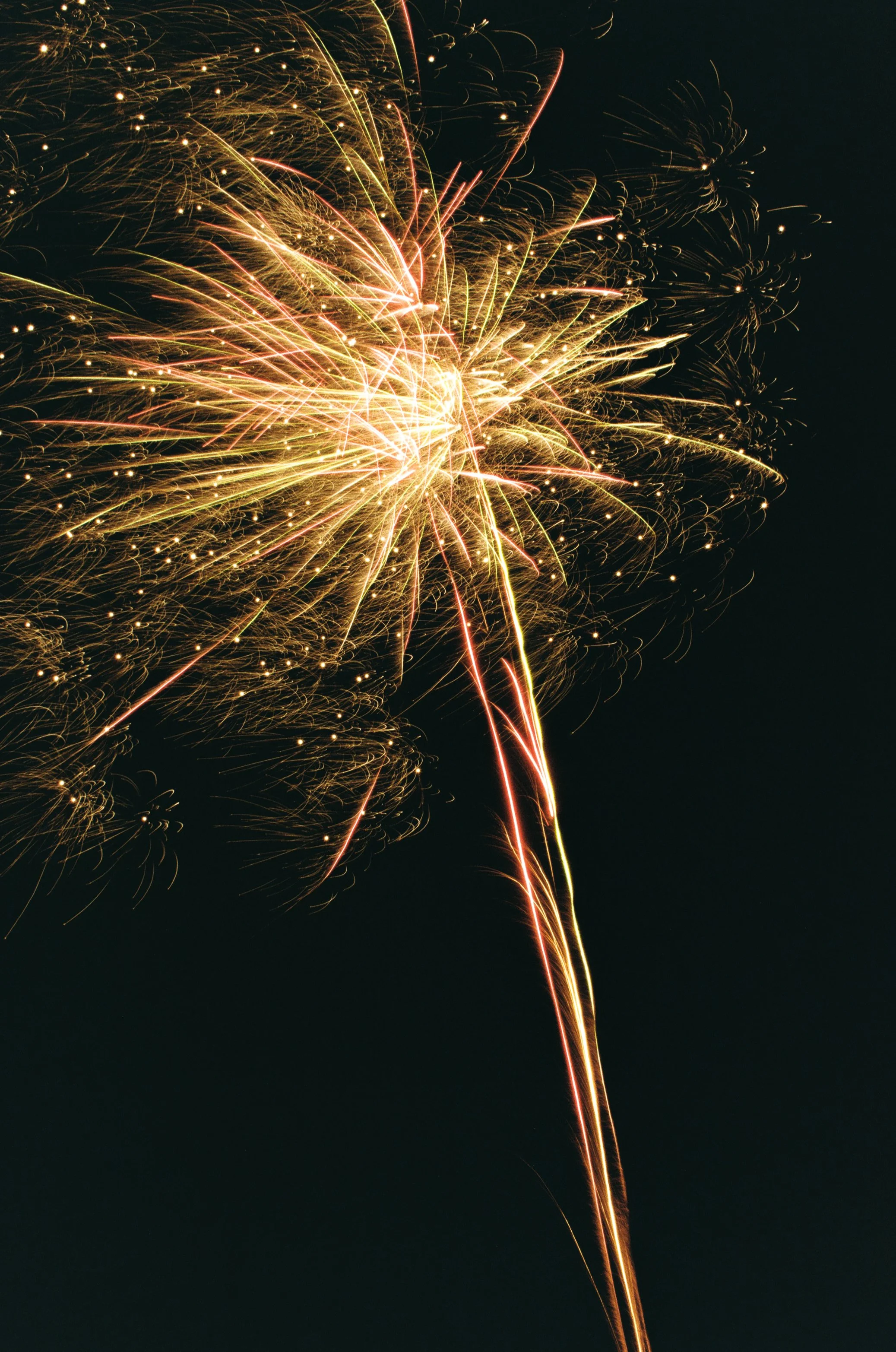 Fireworks display lighting up a dark night sky with golden and red sparks.