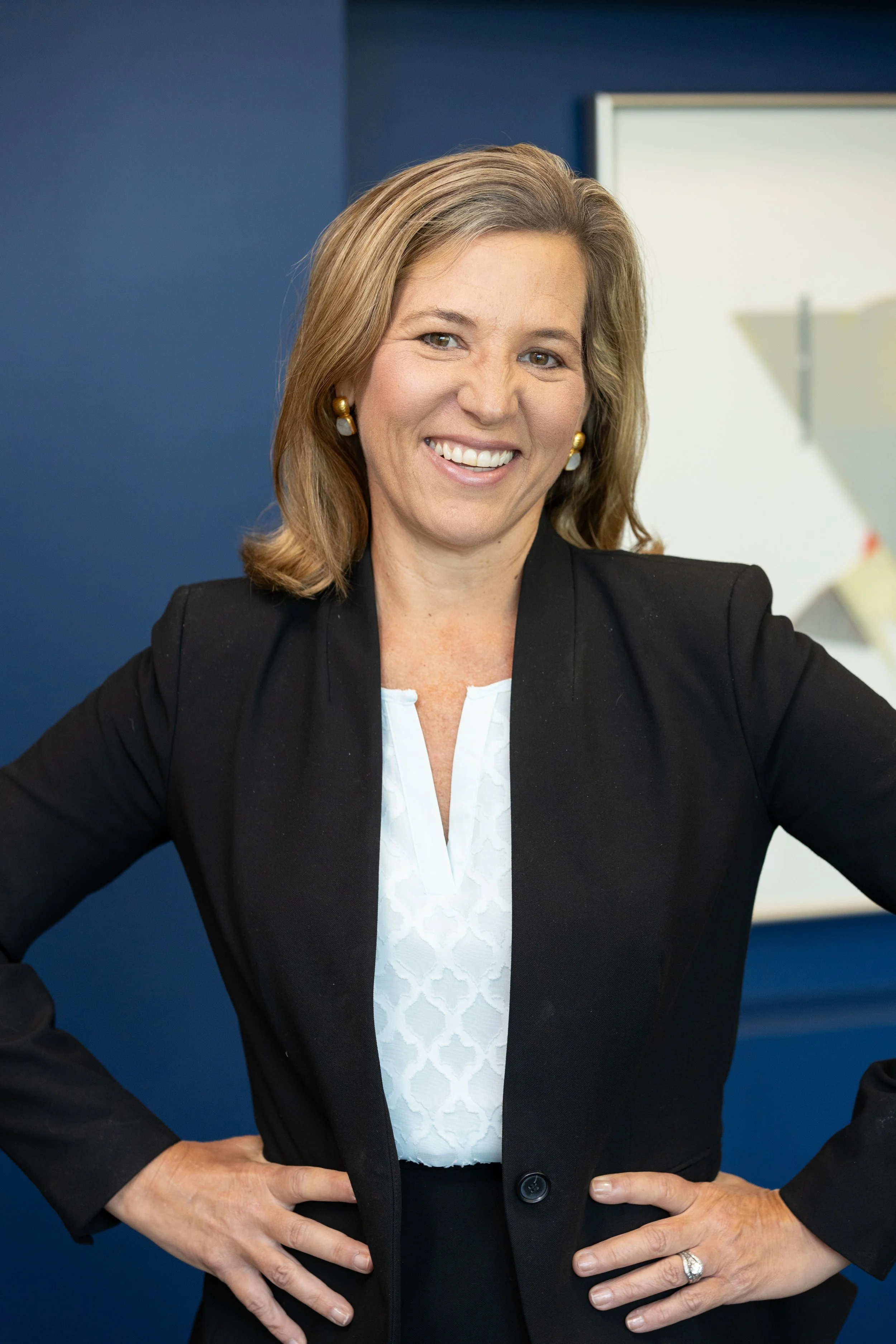 Professional headshot of Meredith S. Jeffries, a white adult woman wearing a white top and black blazer against a navy blue background.